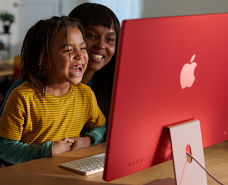 Anggota keluarga tertawa bersama saat menonton acara TV di iMac.